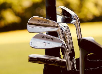 The image shows a set of golf clubs with brands like Titleist and Cleveland, placed in a golf bag.